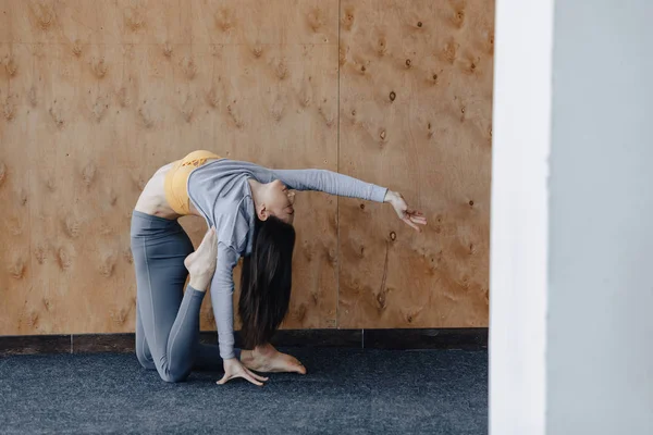 Ahşap bir arka planda yerde Yoga ile Fitness egzersizleri yapan genç çekici kız