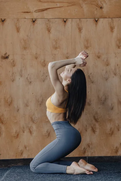 Νέοι ελκυστικό κορίτσι κάνει ασκήσεις γυμναστικής με γιόγκα στο πάτωμα σε ένα ξύλινο φόντο — Φωτογραφία Αρχείου