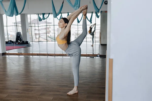 Jong aantrekkelijk meisje op een houten vloer doet yoga, stretching en ontspannen — Stockfoto
