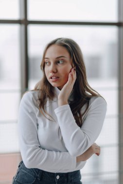 Pencerenin arkasındaki çekici genç kız farklı duygular ve ruh hali gösteriyor. Kapalı alanda hafif arka planda bir kız.