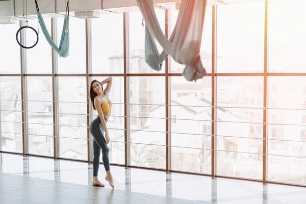 Genç ve çekici kız spor salonunda poz veriyor. Yumuşak vücutlu, formda ve yoga yapıyor.