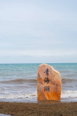 Qinghai Gölü ve taş kaya Qinghai Çin 'de bulutlu bir günde. Çene