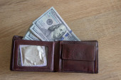 Dollars und Kondome befinden sich in einer Ledertasche. Männer haben ein Portemonnaie mit Must Haves für alles. Im Portemonnaie ist eine große Menge Dollars.