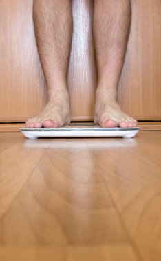 Erkek ayağı tartı terazisinde durur. Bir adam beyaz üzerinde durur ve ağırlığını ölçer.. 