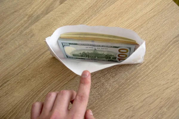Man hand shows an envelope with money. Money dollars lie in a white envelope for an employee. The employee salary lies in an envelope.