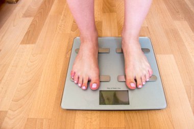 Güzel dişi bacakları terazide duruyor. Gri teraziler yerde duruyor, bir kişi üzerinde tartılırken..