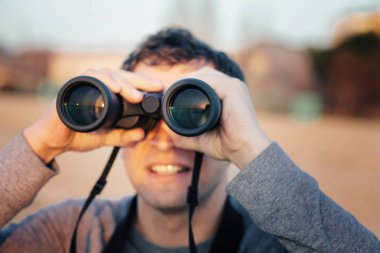 Mutlu genç adam gün batımında dürbünle bakıyor