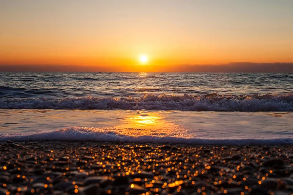 Paisaje marino con un sol poniente en una playa de guijarros — Foto de Stock