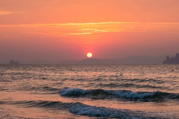Ufukta kıyı şeridi üzerinde bir güneş diski ile Deniz günbatımı manzara