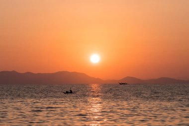 Kayalık kıyıya karşı balıkçı tekneleri siluetleri ile güzel deniz gün batımı