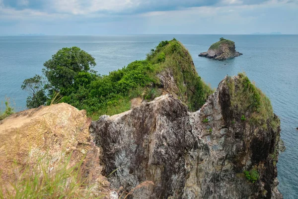 Denizde bitki örtüsüyle kaplı bir kaya. Koh Lanta, Tayland.