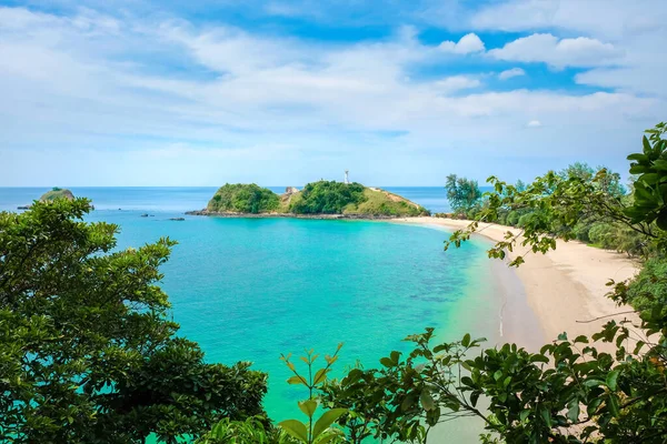 Güzel egzotik deniz manzarası. Terkedilmiş kumsal, sarı temiz kum, turkuaz deniz, bulutlu mavi gökyüzü. Tepede beyaz bir deniz feneri var. Koh Lanta, Tayland.