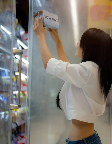 Slim woman in choice of buying low fat daily products  in supermarket shopping mall for heath and diet cause