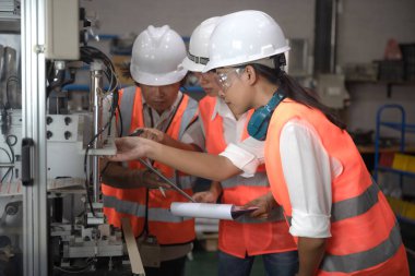 Mühendislik ya da teknik denetim yapan kadın kontrol listesi bölümü ve kalite kontrolü, takım çalışması ile birlikte iş yeri ve denetim sisteminde çalışılmasını sağlamak için makine sistemini kontrol eder.