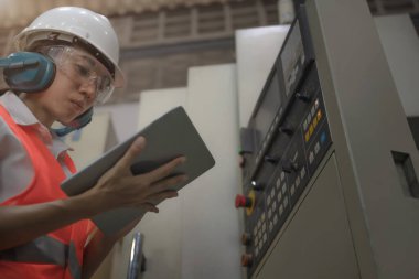 Fabrika deposundaki makine işletiminin kontrol panelinde çalışan kadın mühendisliği. 