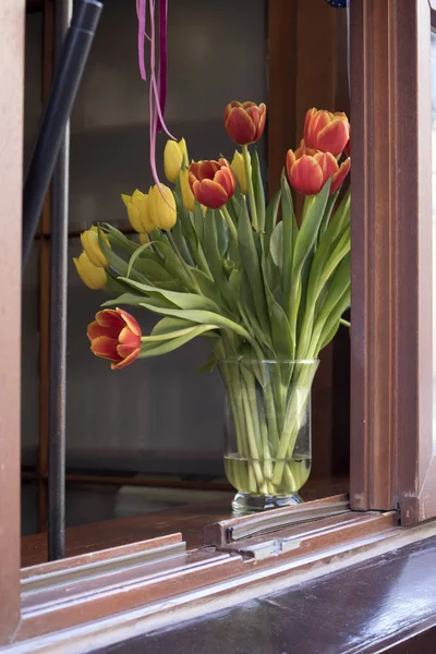 Bukett av röda och gula tulpaner i ett café fönster — Stockfoto