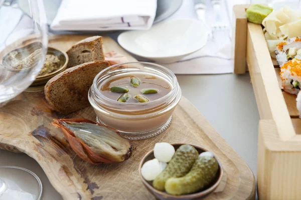 The Pate of foie gras with baked gooseberry and olives on a wooden board in a restaurant — Stock Photo, Image