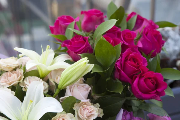 Los Lirios blancos y las rosas de colores en el papel kraft como regalo de cumpleaños — Foto de Stock