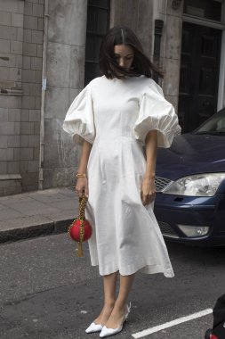 London, Büyük Britanya - 14 Eylül 2018: Londra Moda Haftası sırasında sokakta insanlar. Londra sokaklarında beyaz elbiseli uzun saçlı esmer kız