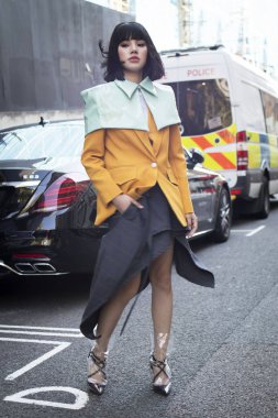 Londra, İngiltere - 14 Eylül 2018: Londra Moda Haftası sırasında sokakta insanlar. Bir sarı ceket ve yeşil cape Çin blogger