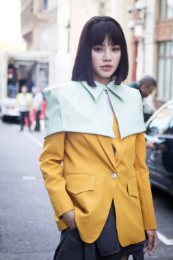 Londra, İngiltere - 14 Eylül 2018: Londra Moda Haftası sırasında sokakta insanlar. Bir sarı ceket ve yeşil cape Çin blogger