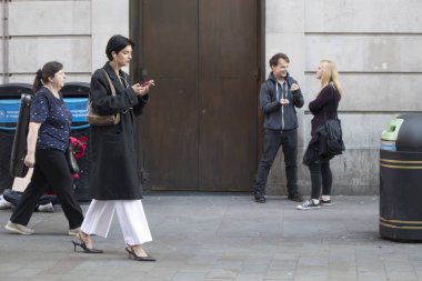 Londra, İngiltere - 15 Eylül 2018 A kalabalık insan Oxford Street boyunca yürüyor. Moda kız beyaz geniş etek ve siyah ceket Sigara