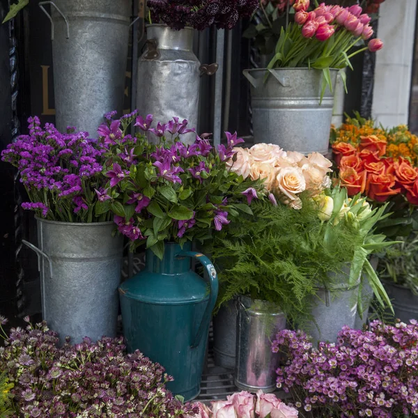 Variedad de flores en la gama lila en cestas para la venta en la entrada de la florería — Foto de Stock