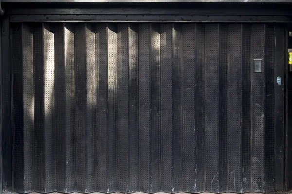 O Portão Corrugado de Ferro Negro. fundo escuro urbano, persianas rolantes — Fotografia de Stock