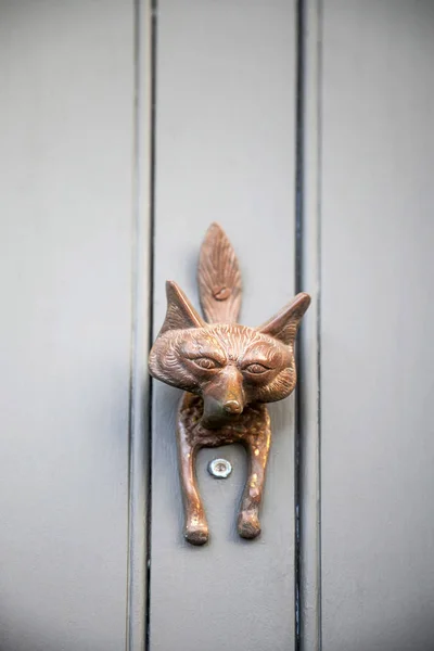 a fox\'s head door knocker on a craft door of a house.