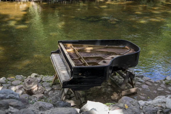 Piano gran abandonné, piano délabré au bord d'une rivière (rivière Vilnia) dans le quartier des artistes Uzupis à Vilnius, Lituanie, ambiance bohème. République d'Uzupis — Photo