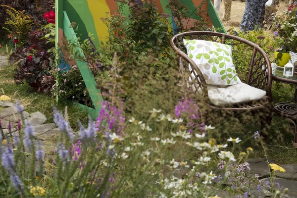 Wicker chairs in garden near the table with a vase with plants. — Stock Photo, Image