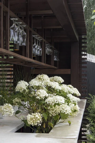 Bar counter in the garden with wine glasses. Hortensia adorns the garden. — Stock Photo, Image