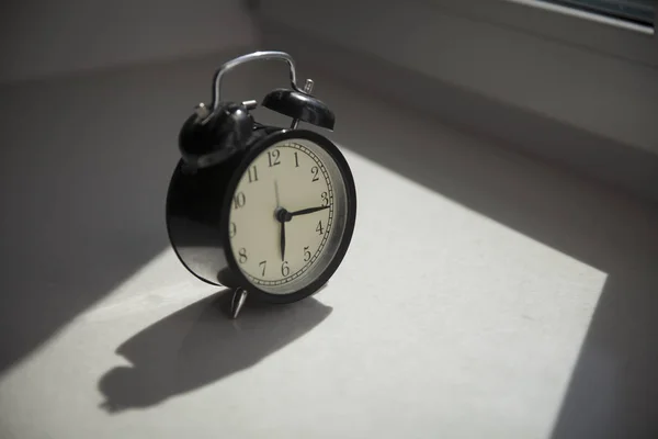 El despertador está en la ventana. Muestra la hora a las seis menos cuarto. . — Foto de Stock