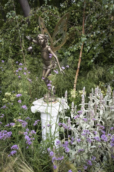 Garden sculpture in the garden in form of fairies with wings among the grass — Stock Photo, Image