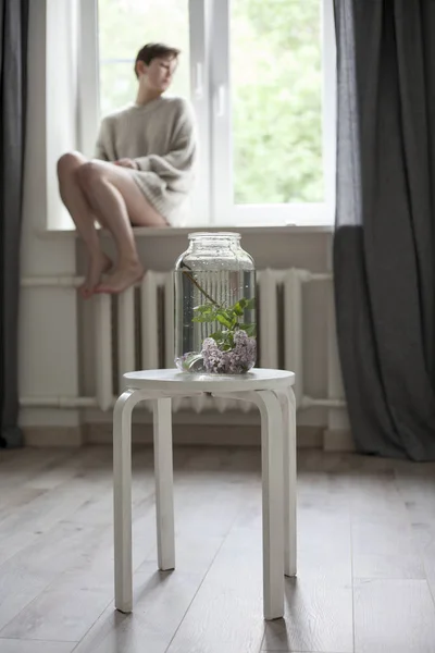 Bouquet of lilac twigs in a transparent green jar on the white chair as a decoration of interior — Stock Photo, Image