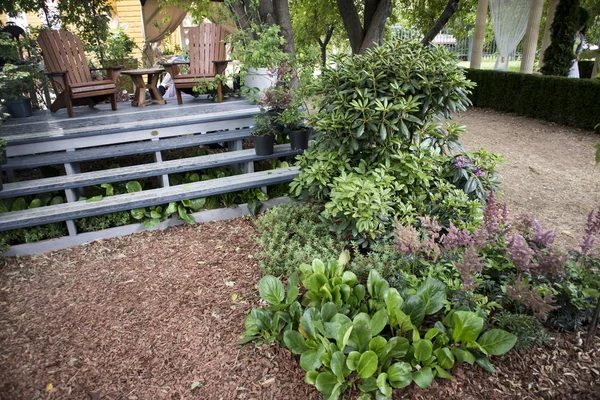 As cadeiras de madeira em um pódio de madeira no jardim entre as plantas — Fotografia de Stock