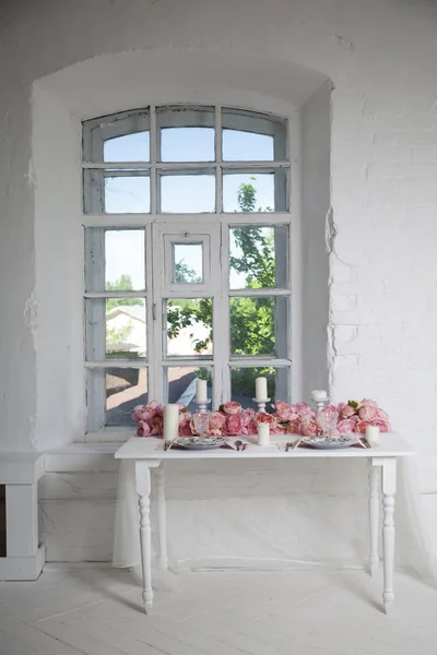 Jídelní stolek u okna zdobí kytice růžových orchidejí, růží a nepřestávali — Stock fotografie