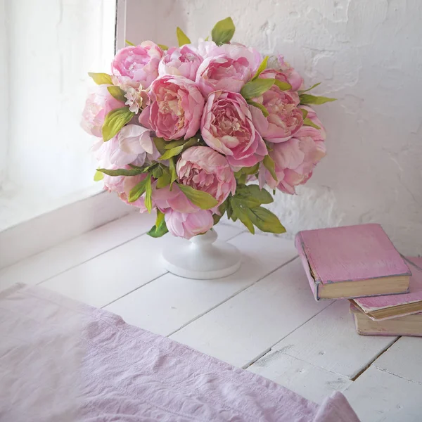 Ramo de orquídeas, peonías, rosas en un jarrón de cerámica y una pila de libros —  Fotos de Stock