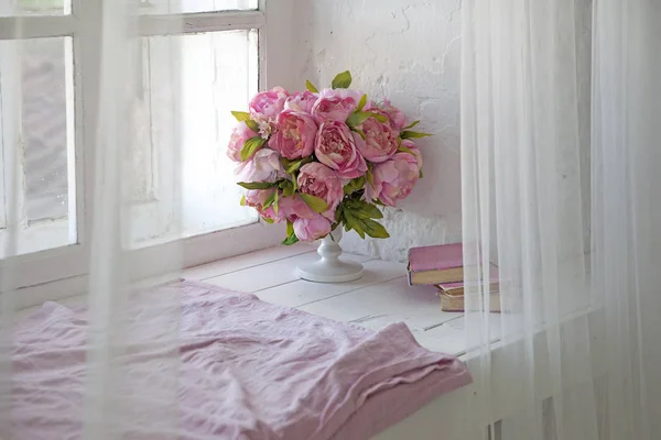 Bouquet of orchids, peonies, roses in a ceramic vase and a stack of books — Stock Photo, Image