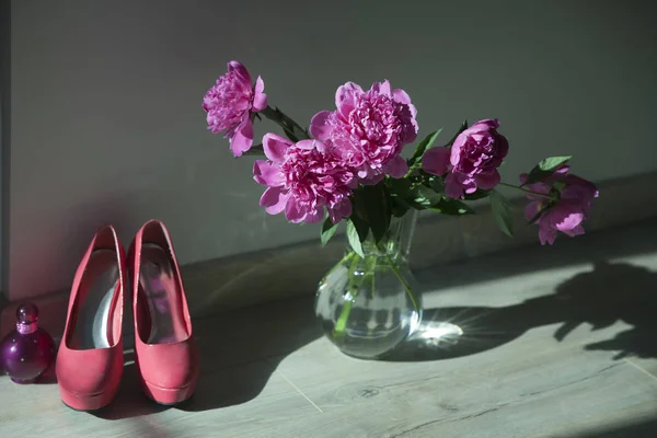 Букет розовых пионов в прозрачной стеклянной вазе на полу — стоковое фото
