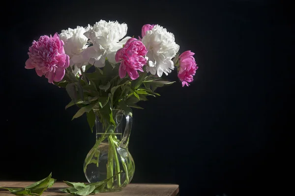 Strauß weißer und roter Pfingstrosen in einer transparenten Vase auf dunklem Hintergrund — Stockfoto