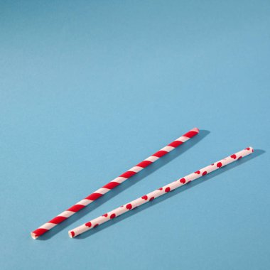 Mavi arka planda kırmızı çizgiler ve kalpler ile iki beyaz kokteyl pipo