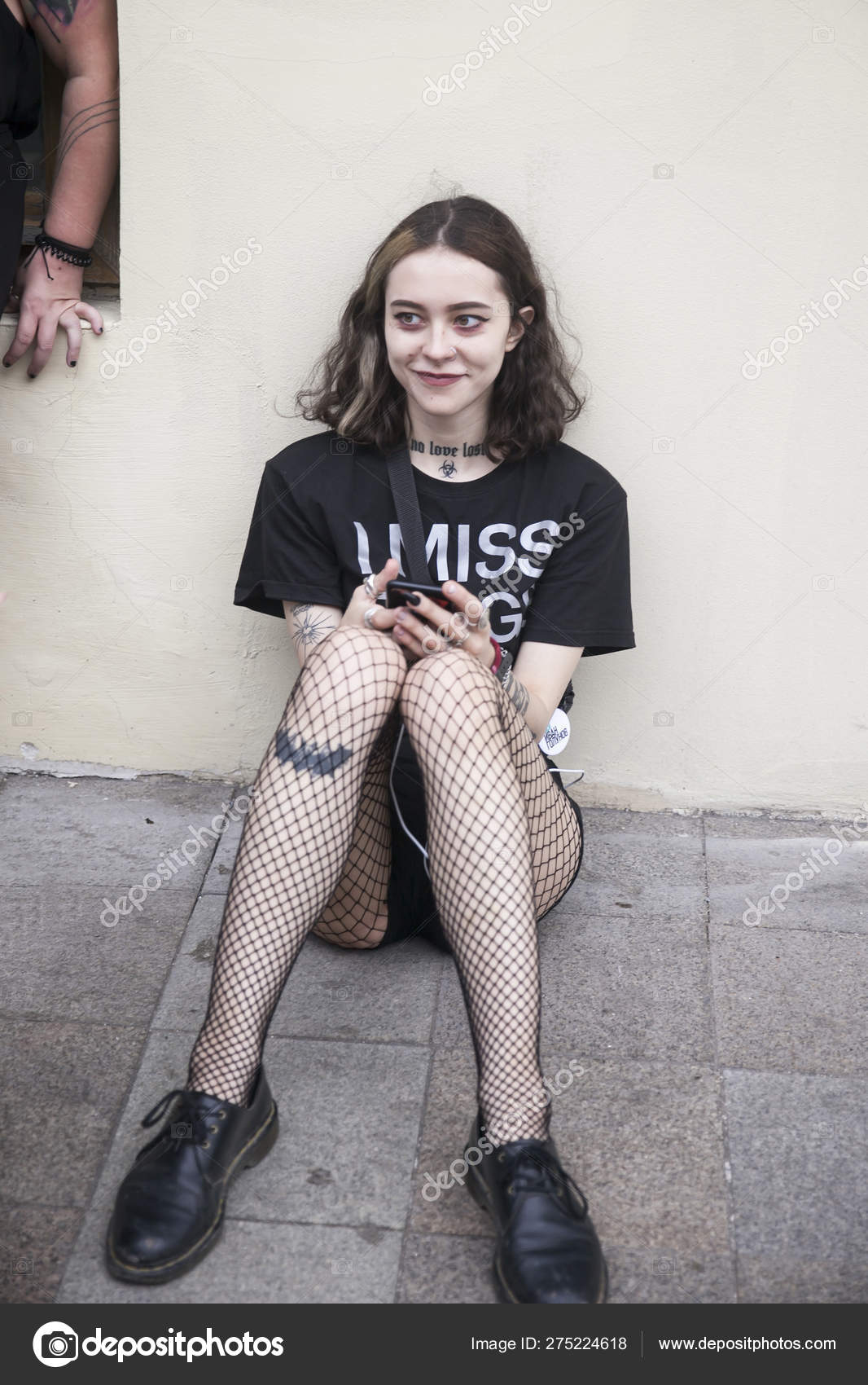 Ragazza gotica in t-shirt nera e collant maglia è seduto sul