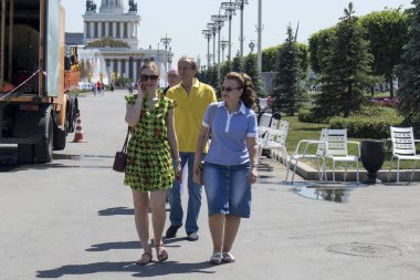 Çok renkli elbiseler içinde iki kız Vdnh parkın cadde boyunca yürüyor