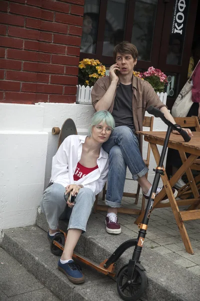 Eine Frau sitzt auf den Stufen eines Cafés und lehnt sich an einen Mann, der an einem Tisch sitzt — Stockfoto