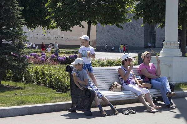 Dwie kobiety z dwójką dzieci siedzą na ławce w parku ulicznym — Zdjęcie stockowe