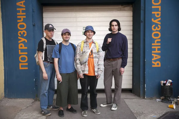 Dört şık giyimli genç beyaz oluklu kapı karşı durmak.