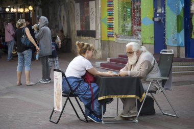 Chiropractor. Uzun saçlı yaşlı gri saçlı adam genç bir kızın elinin kaderini tahmin ediyor