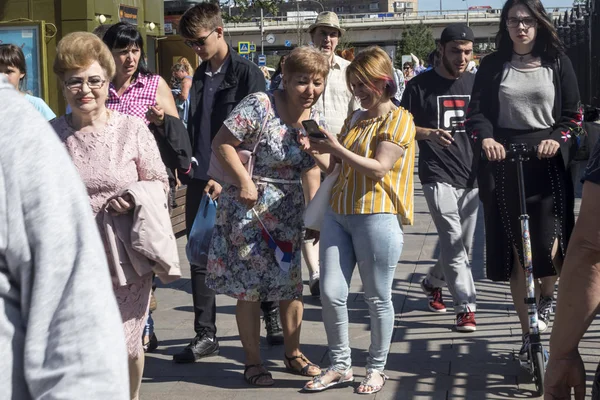 Толпа людей идет по проспекту. Актёры в костюмах забавных животных фотографируются за деньги при прохождении мимо — стоковое фото