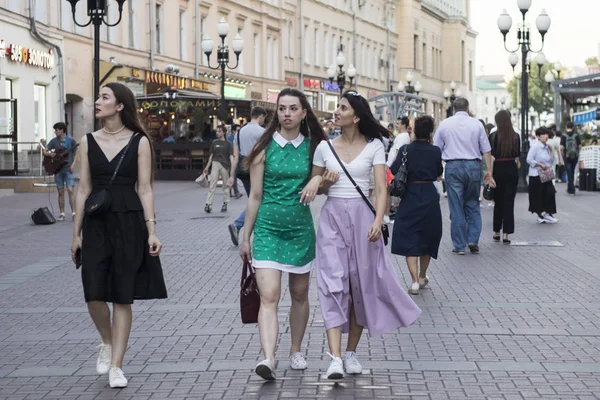 Три девушки в платьях идут по Арбат Стрит в толпе — стоковое фото